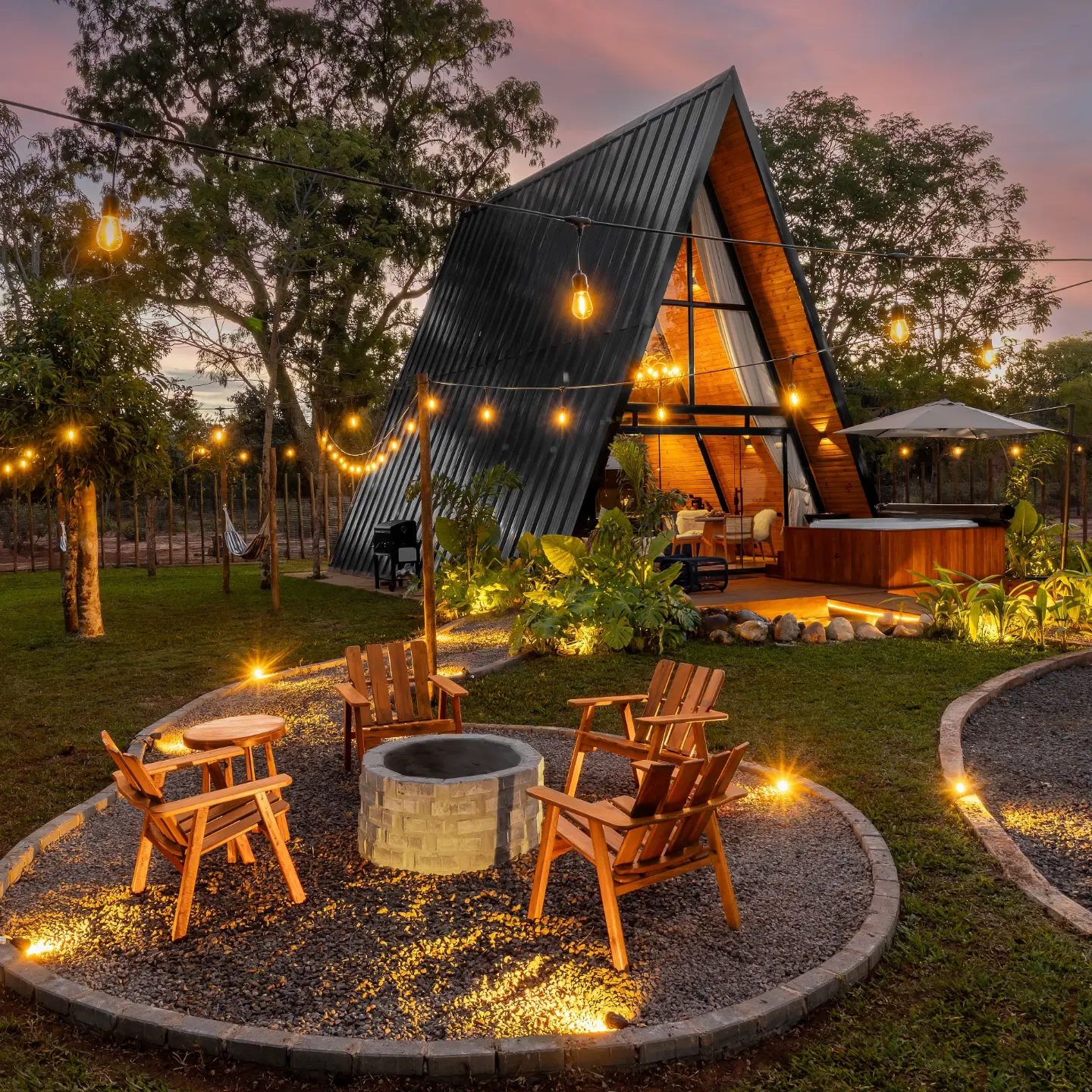 Cabana Zaruna iluminada ao entardecer, com jardim, SPA e espaço de fogueira