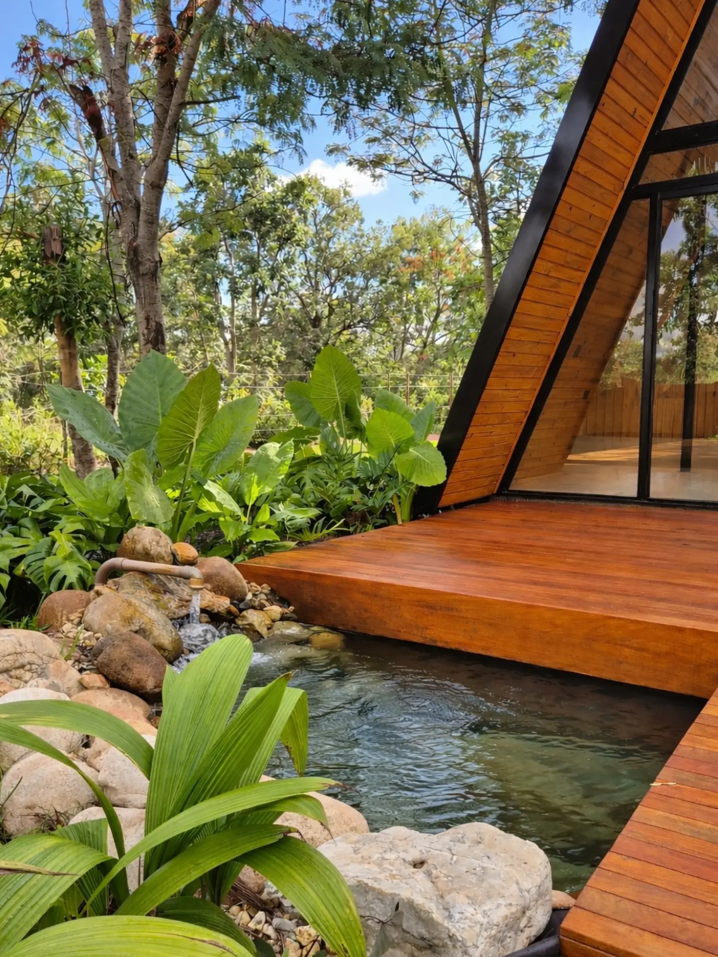 Água, pedras e vegetação junto ao deck da cabana